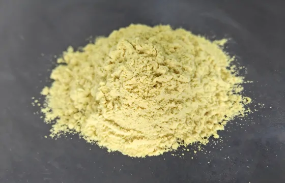一堆呈淡黄色粉末状的聚合硫酸铁，堆放在深灰色的平面背景上